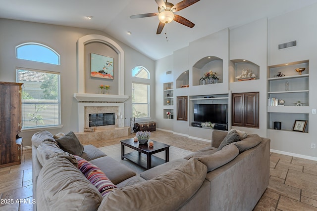 living area with built in features, baseboards, a tiled fireplace, and stone tile flooring