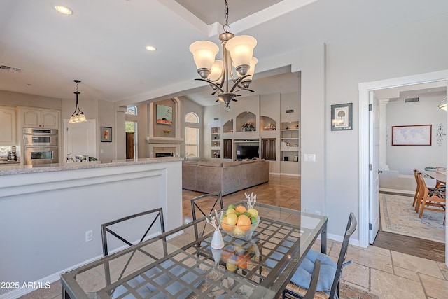 dining area with visible vents, a tile fireplace, recessed lighting, stone tile flooring, and an inviting chandelier