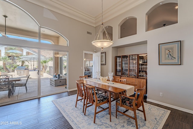 dining space featuring baseboards, a high ceiling, visible vents, and dark wood finished floors