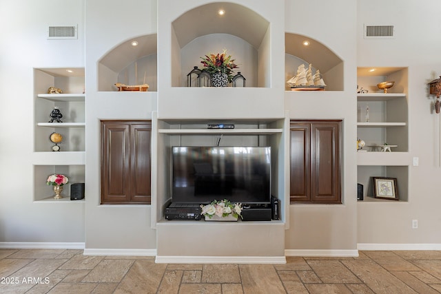 unfurnished living room with baseboards, visible vents, stone tile flooring, and built in shelves