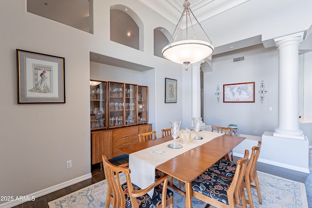 dining area with baseboards, visible vents, wood finished floors, and decorative columns