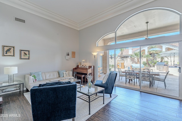 living room with visible vents, crown molding, and wood finished floors