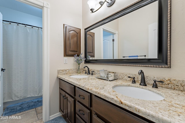 full bath with a shower with curtain, double vanity, stone tile flooring, and a sink