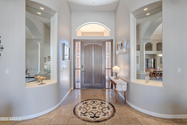 foyer featuring stone tile flooring, baseboards, and ornate columns