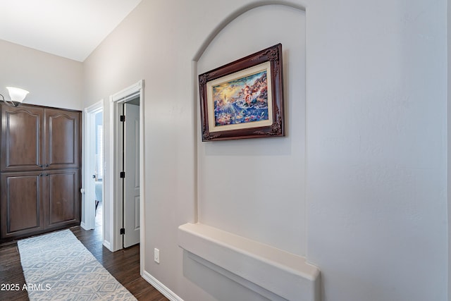 corridor featuring dark wood-type flooring and baseboards