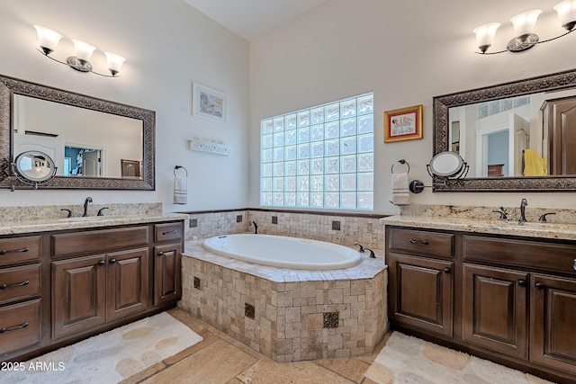 bathroom with a bath, a sink, and two vanities