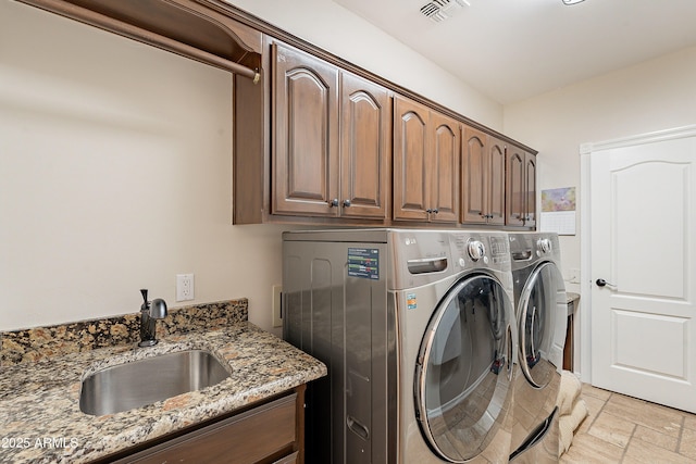 laundry area with washing machine and clothes dryer, a sink, cabinet space, and visible vents