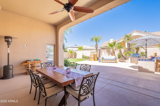 view of patio / terrace with a fenced backyard, outdoor dining space, an outdoor kitchen, and a ceiling fan