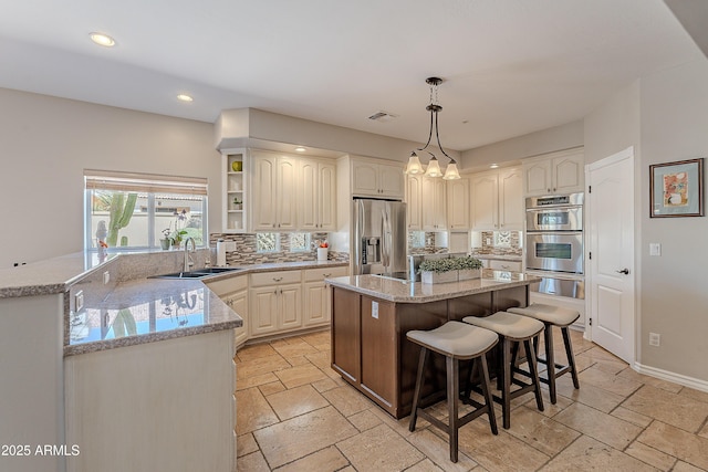 kitchen with stone tile floors, a sink, backsplash, appliances with stainless steel finishes, and visible vents