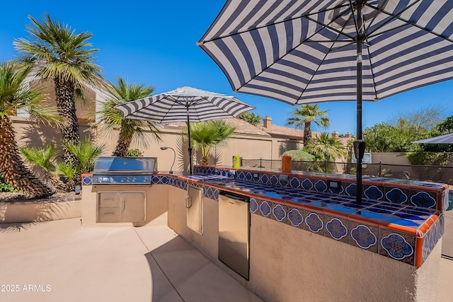 view of patio featuring a grill, fence, and exterior kitchen