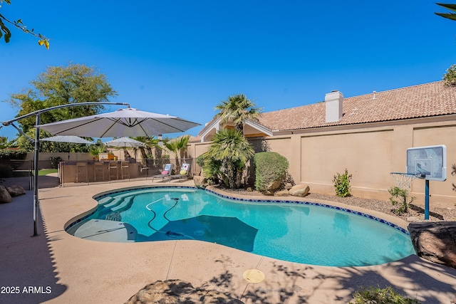 view of swimming pool featuring a patio, fence, a fenced in pool, and outdoor dry bar