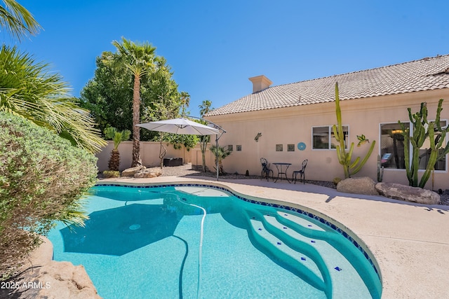 outdoor pool with fence and a patio area