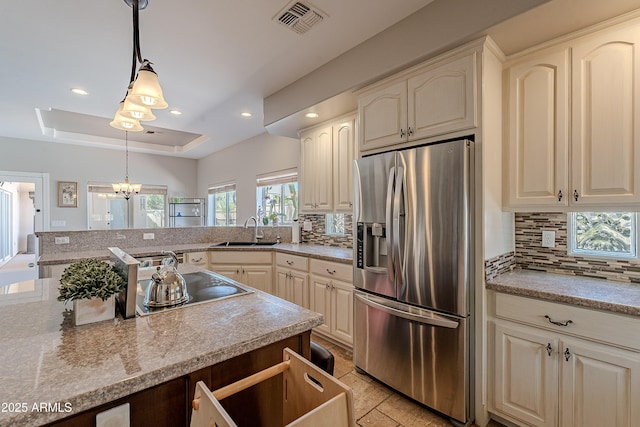 kitchen featuring visible vents, a raised ceiling, hanging light fixtures, a sink, and stainless steel fridge with ice dispenser