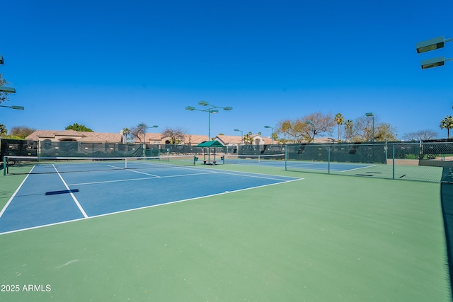 view of tennis court with community basketball court and fence