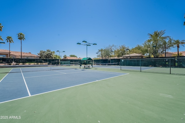 view of tennis court with community basketball court and fence