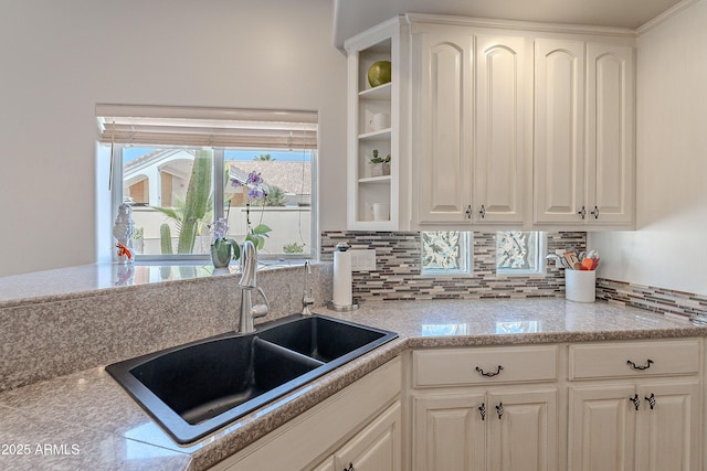 kitchen with light countertops, a sink, white cabinets, and tasteful backsplash