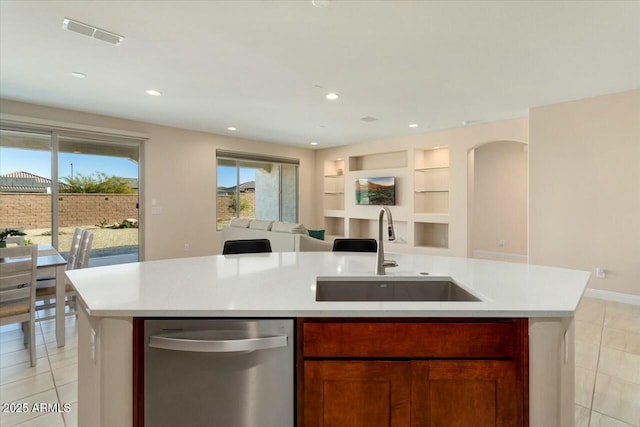 kitchen featuring sink, stainless steel dishwasher, built in features, light tile patterned floors, and an island with sink