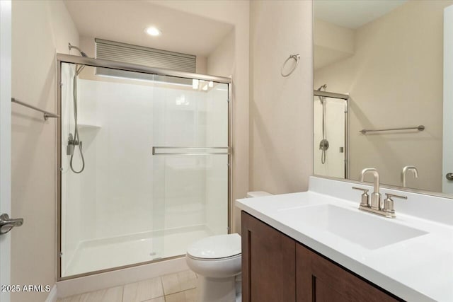 bathroom featuring tile patterned floors, vanity, toilet, and a shower with door