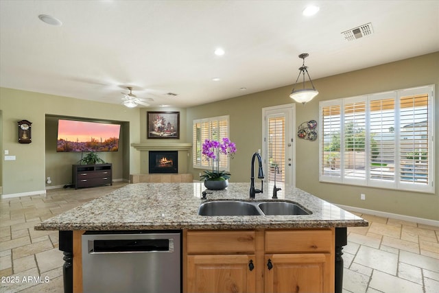 kitchen with stainless steel dishwasher, a fireplace, a sink, and stone tile floors