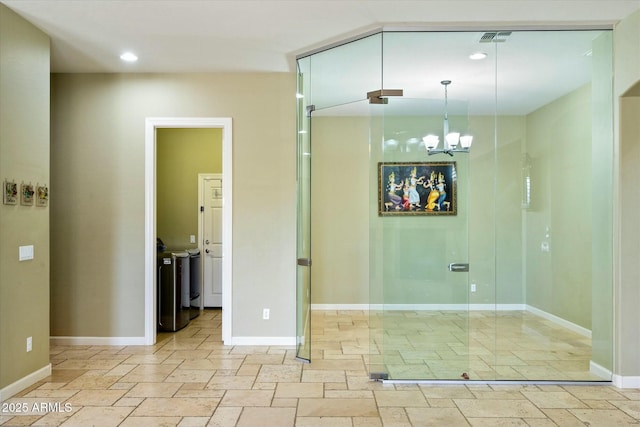 interior space with baseboards, stone tile floors, visible vents, and a notable chandelier