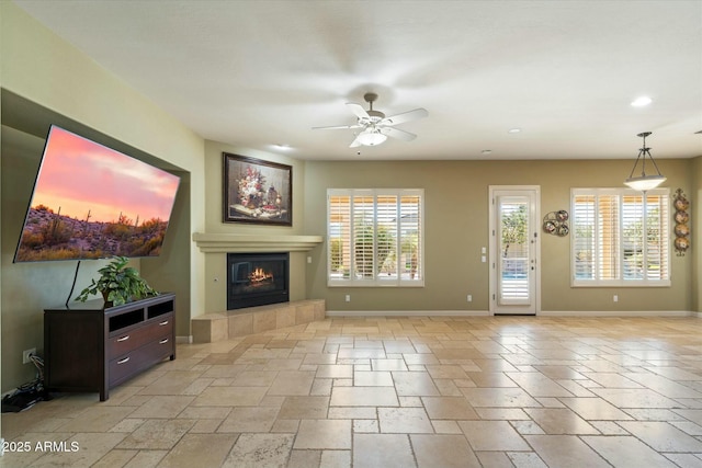 unfurnished living room featuring a wealth of natural light, a tiled fireplace, and stone tile flooring