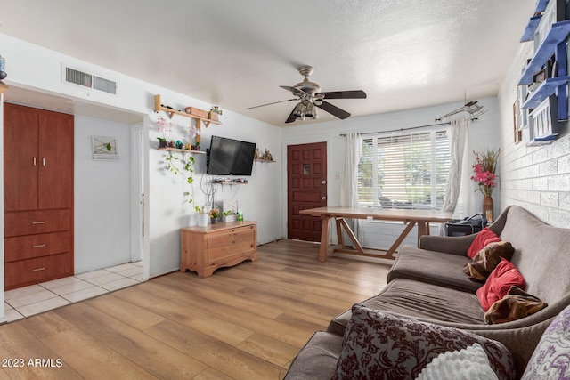 living room featuring ceiling fan, a textured ceiling, and light hardwood / wood-style flooring