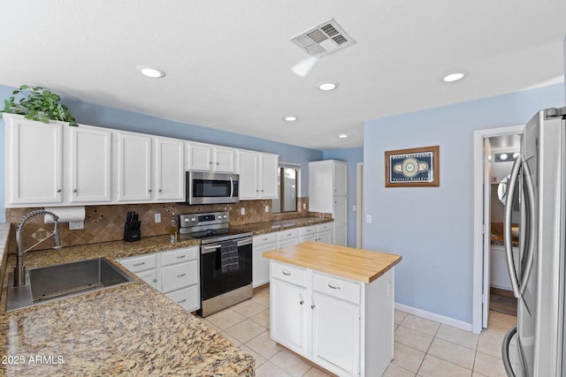 kitchen with sink, backsplash, white cabinetry, a center island, and stainless steel appliances