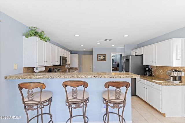 kitchen featuring stainless steel appliances, white cabinetry, kitchen peninsula, and decorative backsplash