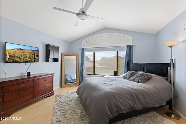 bedroom with ceiling fan, vaulted ceiling, and light wood-type flooring