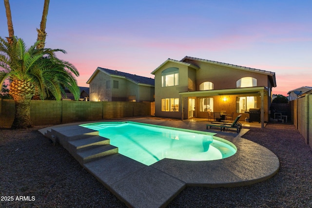 pool at dusk with a patio area