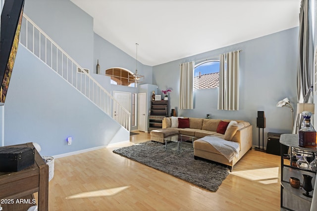 living room featuring high vaulted ceiling, a chandelier, and light wood-type flooring