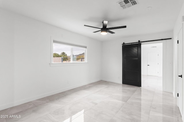 unfurnished bedroom featuring a barn door and ceiling fan