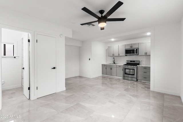 kitchen featuring sink, gray cabinetry, decorative backsplash, ceiling fan, and stainless steel appliances