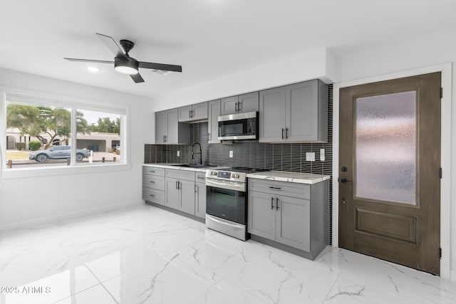 kitchen featuring appliances with stainless steel finishes, sink, decorative backsplash, and gray cabinetry