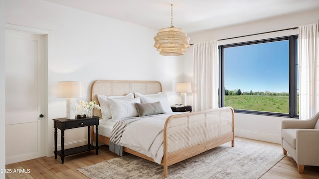 bedroom featuring baseboards, an inviting chandelier, and wood finished floors