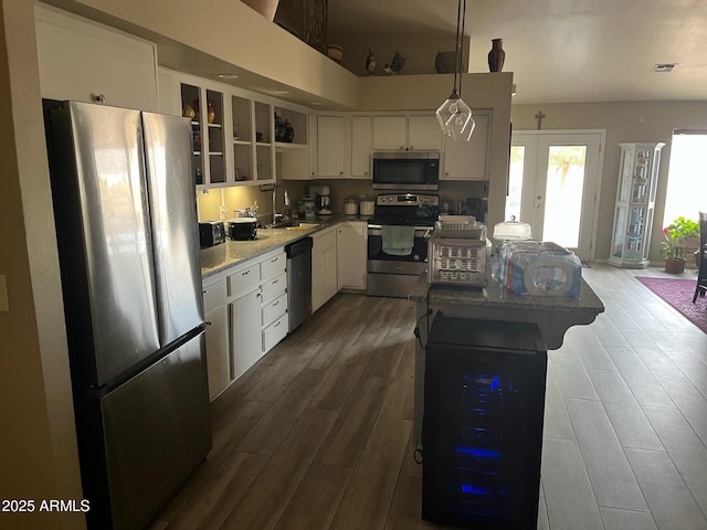 kitchen featuring light stone counters, hanging light fixtures, white cabinetry, and appliances with stainless steel finishes