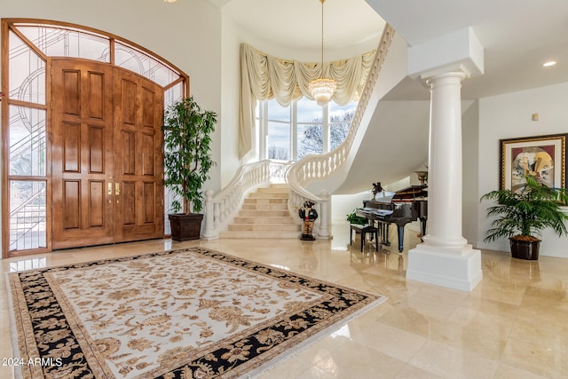 tiled foyer featuring an inviting chandelier and decorative columns