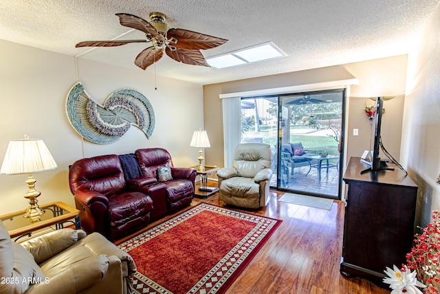 living room featuring dark hardwood / wood-style flooring, ceiling fan, a skylight, and a textured ceiling