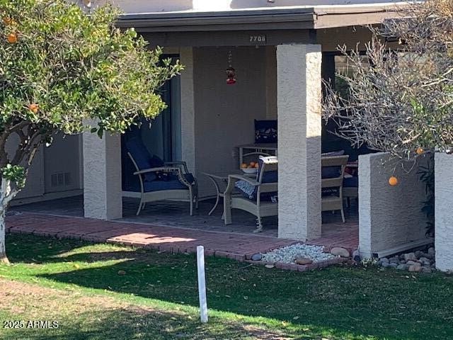 view of exterior entry with a yard and a patio area