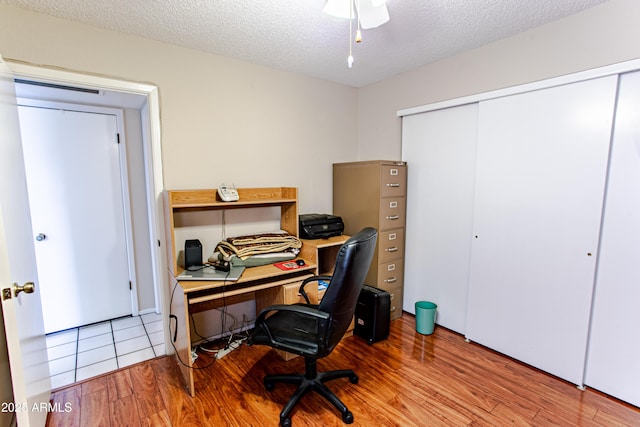 home office featuring light hardwood / wood-style flooring and a textured ceiling