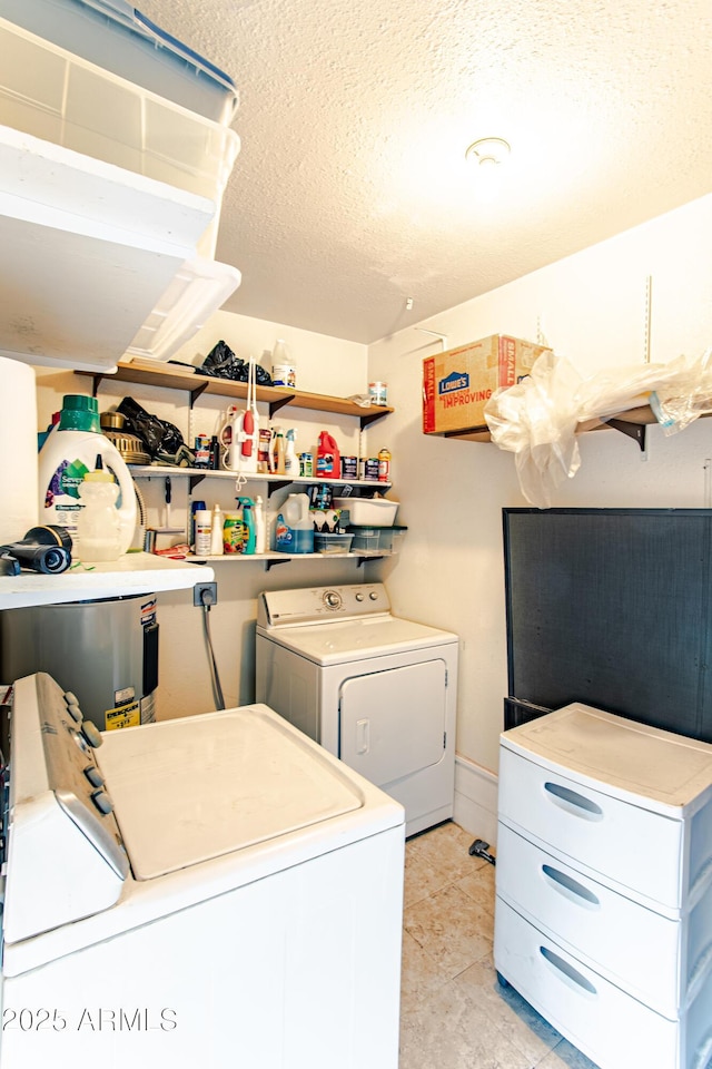 laundry area with washing machine and dryer, a textured ceiling, and light tile patterned floors