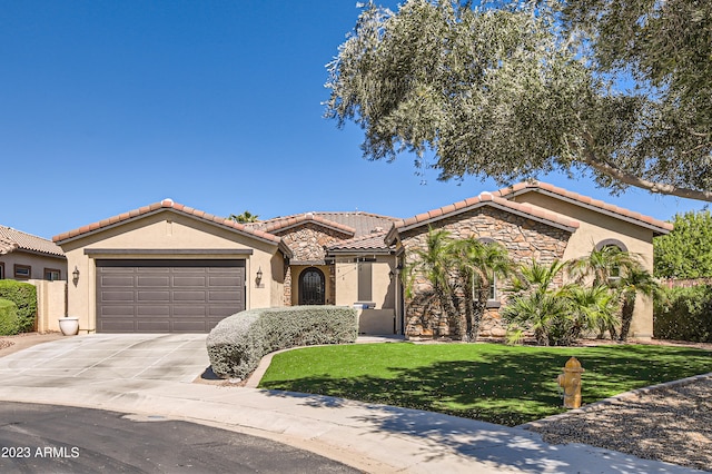 mediterranean / spanish home with a garage, stone siding, concrete driveway, and stucco siding