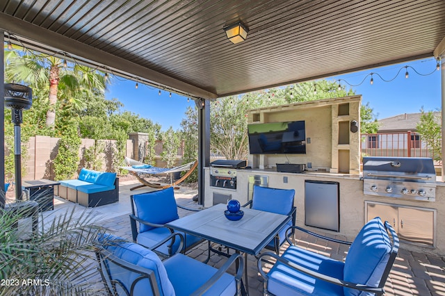 view of patio featuring outdoor lounge area, fence, grilling area, and an outdoor kitchen