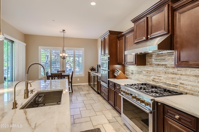 kitchen with high end stainless steel range, tasteful backsplash, hanging light fixtures, a sink, and under cabinet range hood