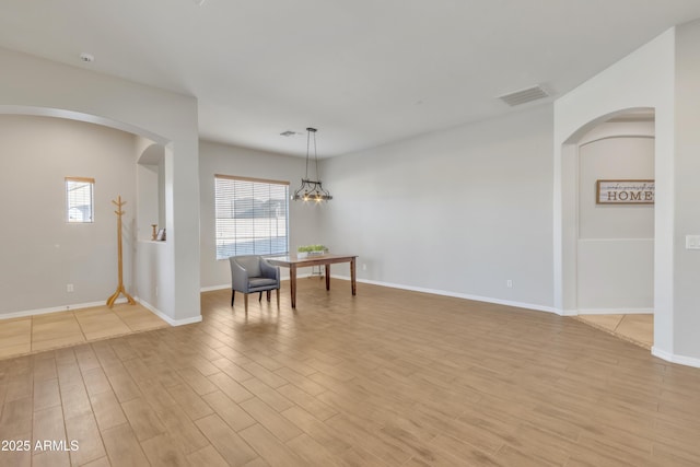 empty room with a chandelier and light hardwood / wood-style floors