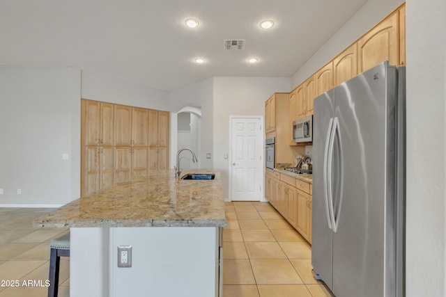 kitchen with stainless steel appliances, an island with sink, sink, and light tile patterned flooring