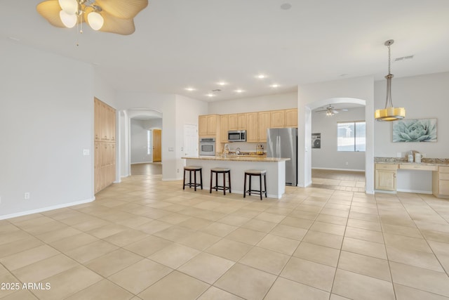 kitchen featuring stainless steel appliances, a kitchen island, light tile patterned floors, and decorative light fixtures