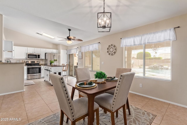 dining space featuring lofted ceiling, ceiling fan with notable chandelier, light tile patterned flooring, and baseboards