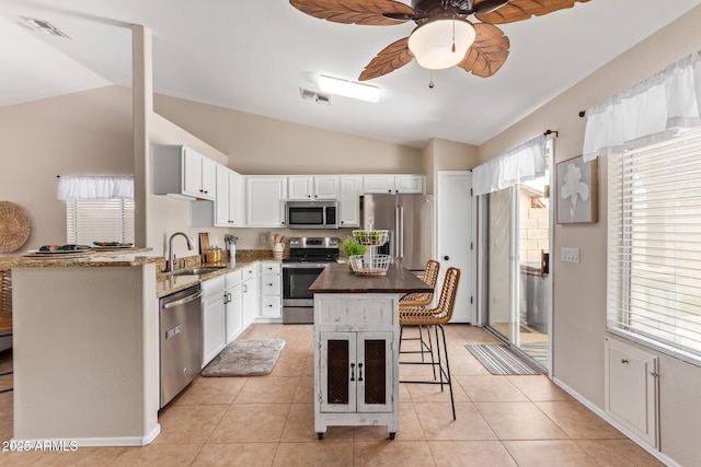 kitchen featuring vaulted ceiling, appliances with stainless steel finishes, a sink, and a breakfast bar