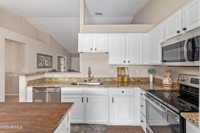 kitchen featuring vaulted ceiling, appliances with stainless steel finishes, a sink, and white cabinets